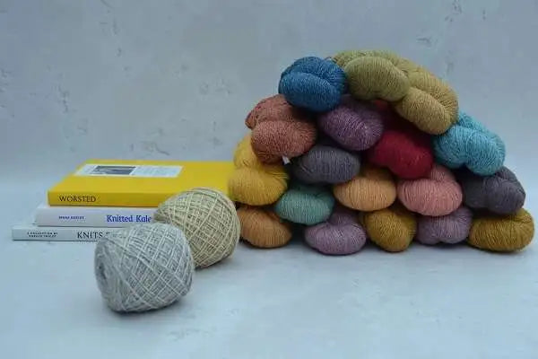 Hand dyed yarn. Colourful yarn balls stacked on a white surface with books about knitting.