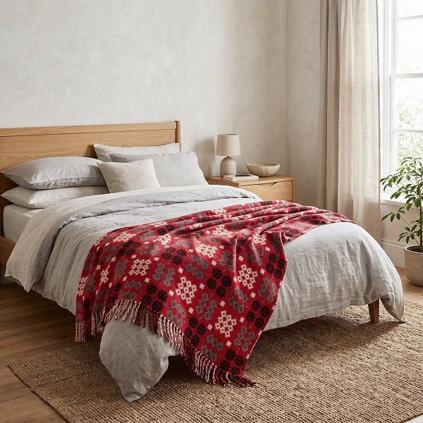 Draig Goch Welsh blanket. Draped over a double bed in a modern bedroom.