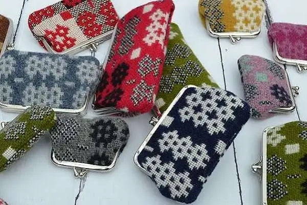Collection of small woven Welsh tapestry purses in various patterns and colours on a white background
