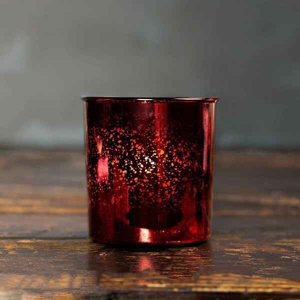 Red Christmas glass candle holder on a wooden surface with a blurred background