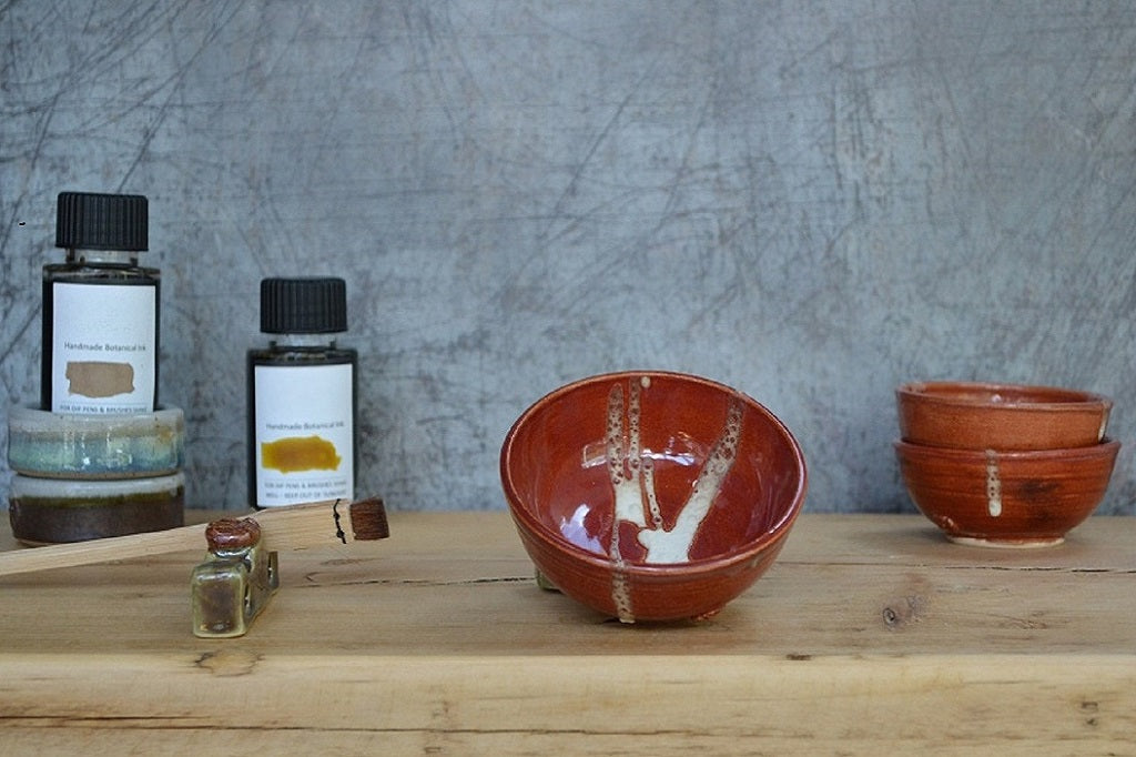 Handmade water  bowls and bottles on a wooden surface with a textured gray wall background