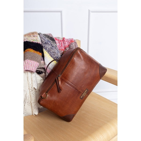 ReDesigned Project 80 Brown leather bag on a wooden chair with a colourful sweater in the background