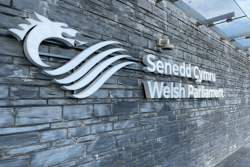 Logo of Senedd Cymru Welsh Parliament on a stone wall