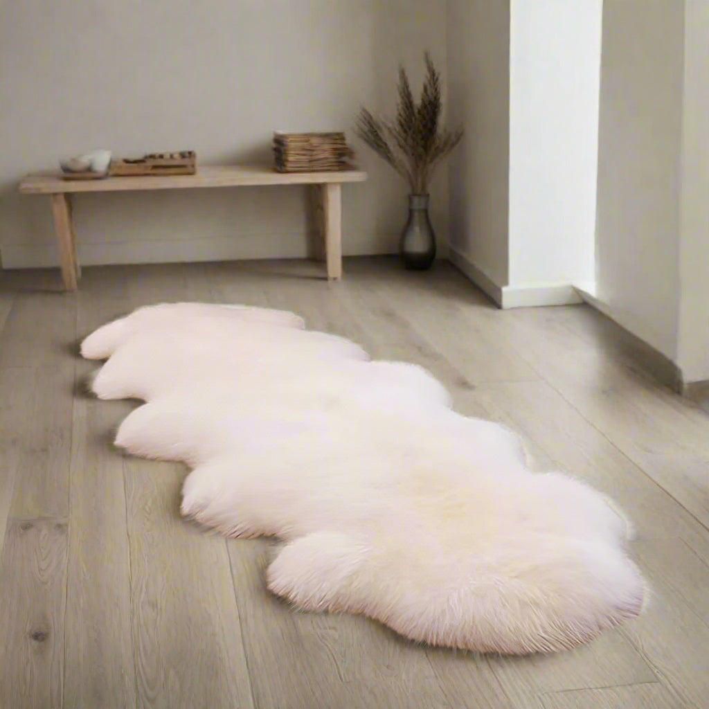 Natural Off White double sheepskin rug on a wooden floor in a minimalistic room.