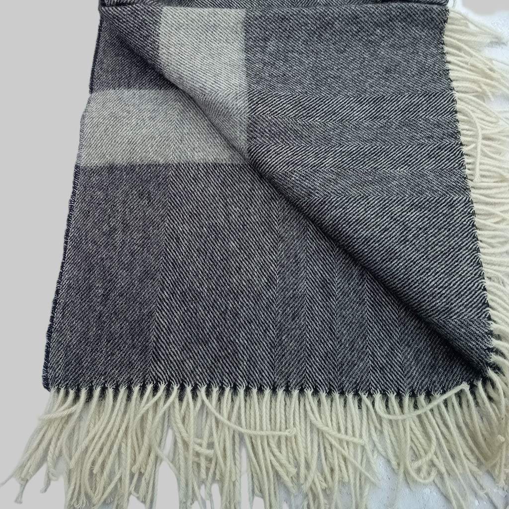 Welsh blanket, Pembroke. Grey and white check blanket with fringes on a light grey background