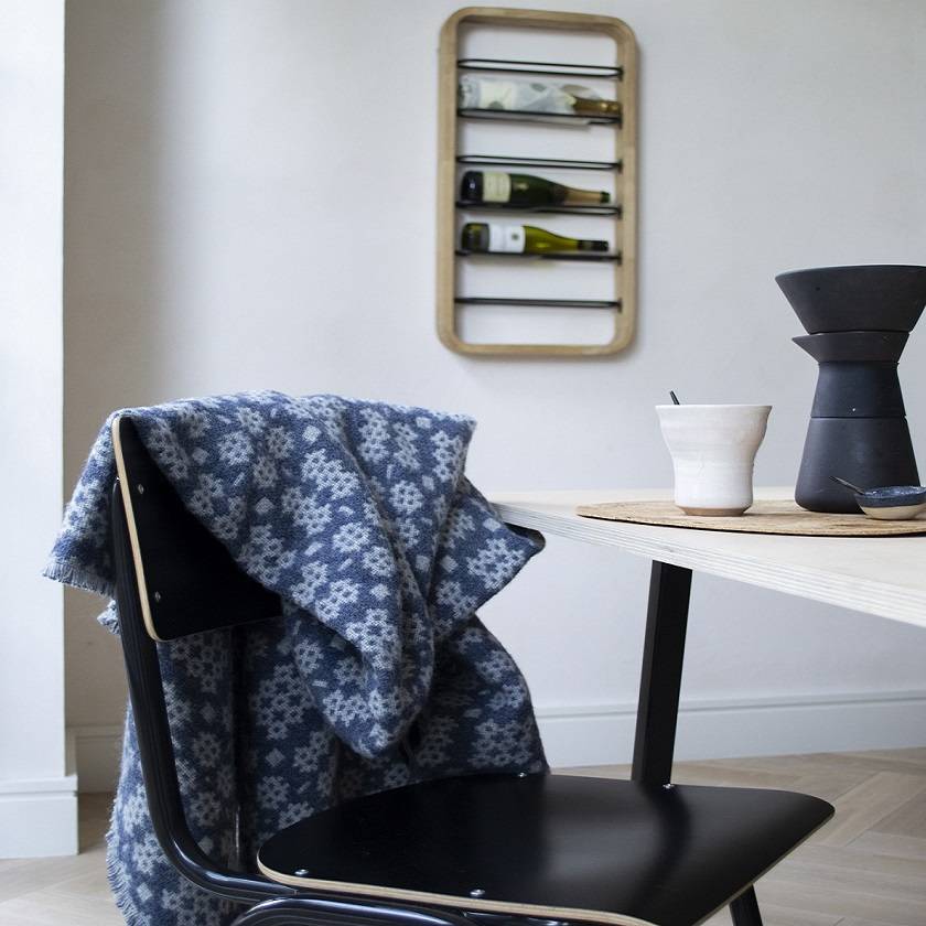 Welsh blanket. Chair with a blue patterned blanket draped over it, next to a table with a coffee maker and cup.