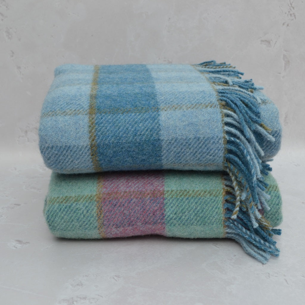 Two plaid blankets stacked on a light gray surface