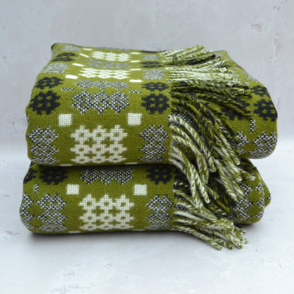 TirGlas Welsh blanket woven in  the  Caernarfon portcullis design. Moss Green weft and a cream and black warp. This tapestry style blanket is the perfect blend of tradition, quality, and modern style for any room in your home. Double cloth weaving produces full reversible blankets