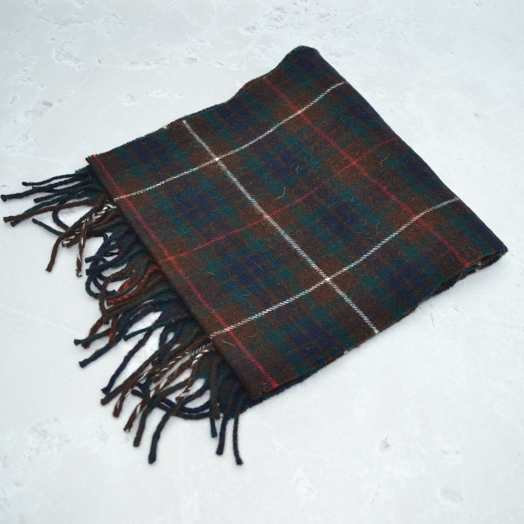 Plaid scarf with fringes on a light gray background