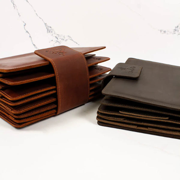 Set of brown leather coasters with a holder on a white surface